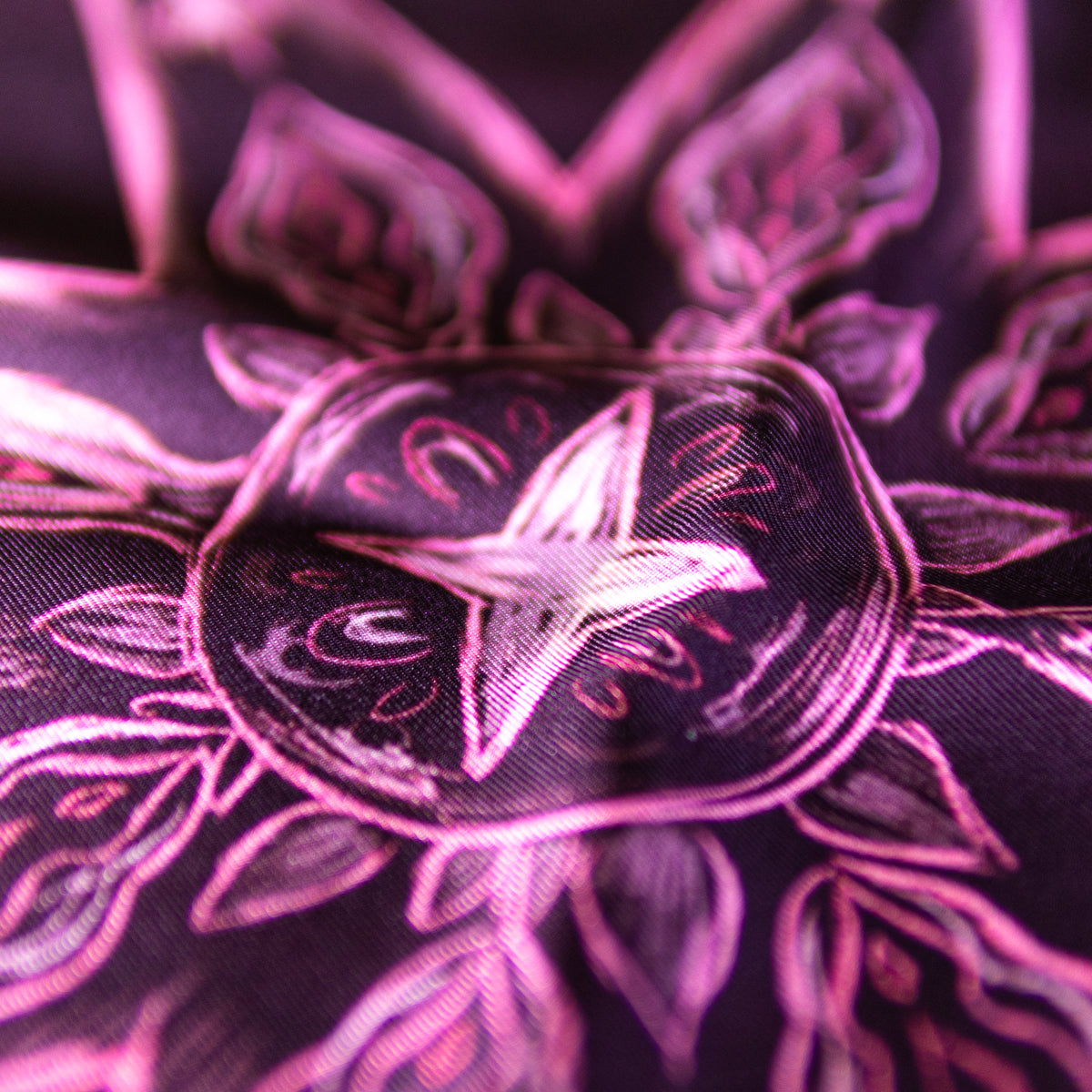 A close-up of a dark burgundy mulberry silk fabric with a bright pink starburst pattern. Hand rolled