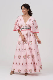 Woman wearing a pink floral maxi dress with a white background