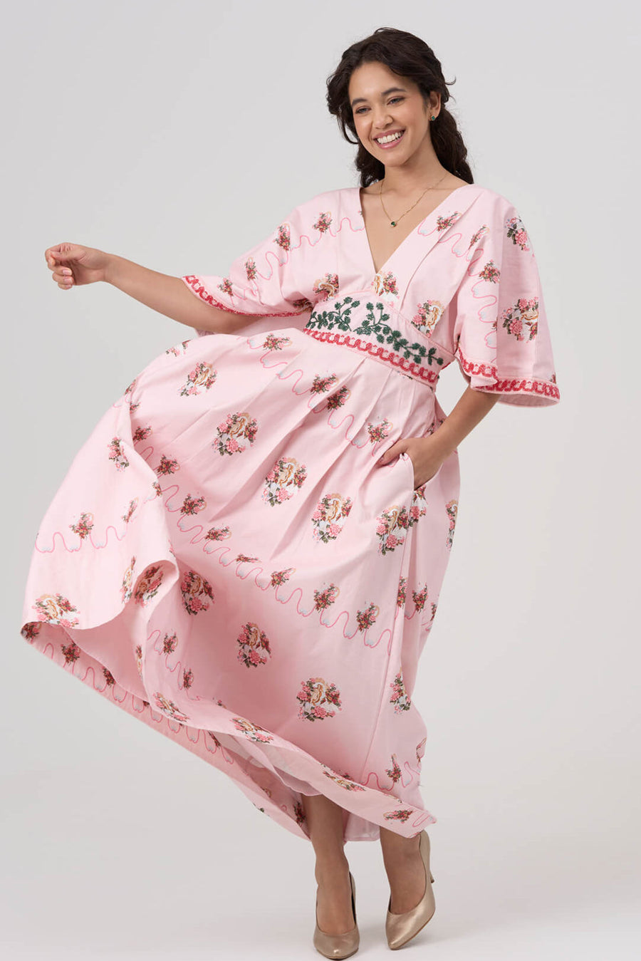 Woman wearing a pink floral maxi dress on a white background