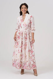 Woman wearing a white and pink floral maxi dress on a white background
