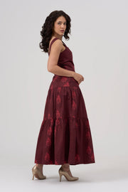 Woman wearing a bordeaux maxi dress with floral patterns on a white background