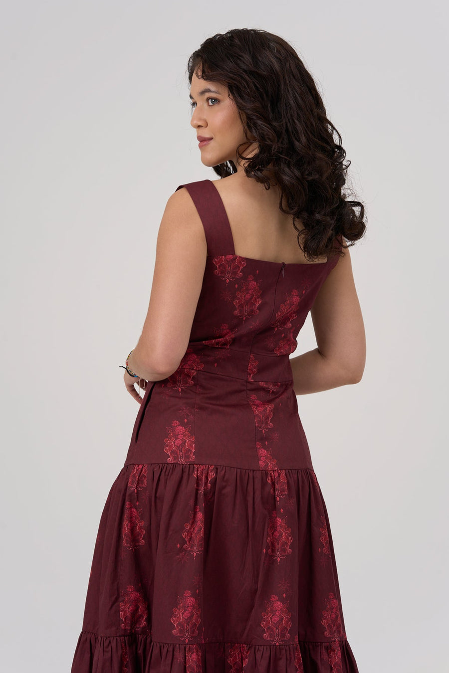 Woman wearing a burgundy maxi dress with floral patterns on a white background