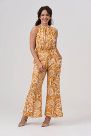 Woman wearing a yellow floral jumpsuit on a white background
