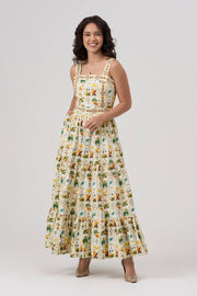 Woman wearing a white and green floral maxi dress on a white background