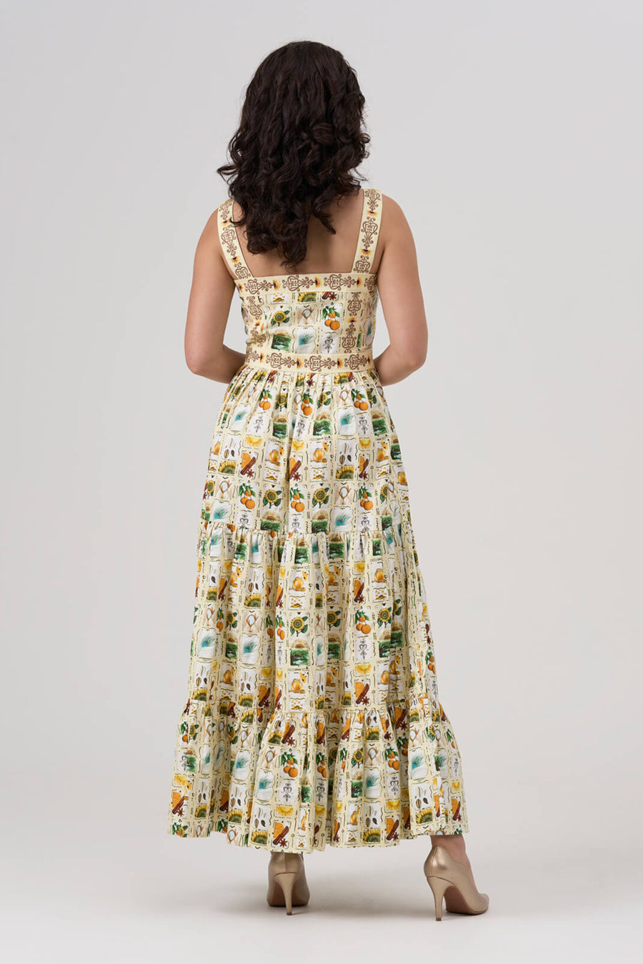 A woman wearing a sleeveless maxi dress with a floral and animal print on a plain background
