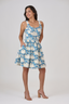 Front view of the Athena’s Triumph knee-length dress in ivory and blue hemp-cotton, with wide straps, fitted bodice, tiered skirt, and side pockets