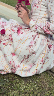 Woman wearing a white and pink floral maxi dress on a white background